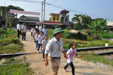 Các thành viên Tổ tự quản ATGT đường sắt xã Đào Thịnh hướng dẫn học sinh đi qua điểm giao cắt giữa đường bộ và đường sắt trong giờ cao điểm.