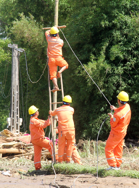 Công nhân Điện lực Nghĩa Lộ dựng cột tạm và kéo dây để nhanh chóng cấp điện cho nhân dân.