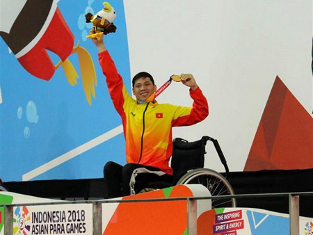Vận động viên Võ Thanh Tùng tự hào giơ cao tấm Huy chương vàng thứ 3 tại Asian Para Games 2018.