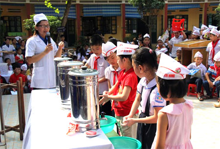 Cán bộ Trung tâm Kiểm soát bệnh tật hướng dẫn học sinh Trường Tiểu học Kim Đồng, thành phố Yên Bái rửa tay bằng xà phòng trước khi ăn.