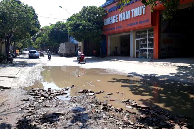 Gạch đá và một vũng nước lớn tù đọng lâu ngày trên mặt đường Trần Bình Trọng.