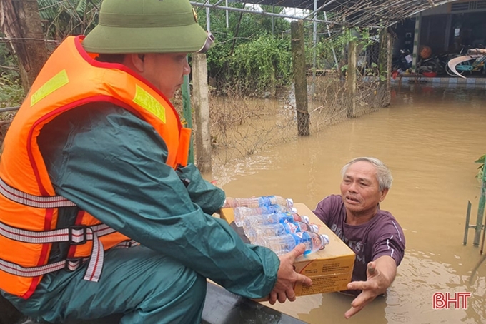 Những hộ dân đang mắc kẹt do ngập lũ nặng lội ra nhận tiếp tế lương thực, nước uống tại xã Cẩm Duệ, huyện Cẩm Xuyên, tỉnh Hà Tĩnh.