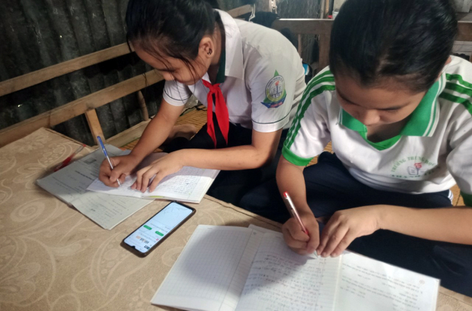 Hai chị em (lớp 6 và 8) cùng một nhà ở Cần Thơ học online chung trên điện thoại di động của mẹ.