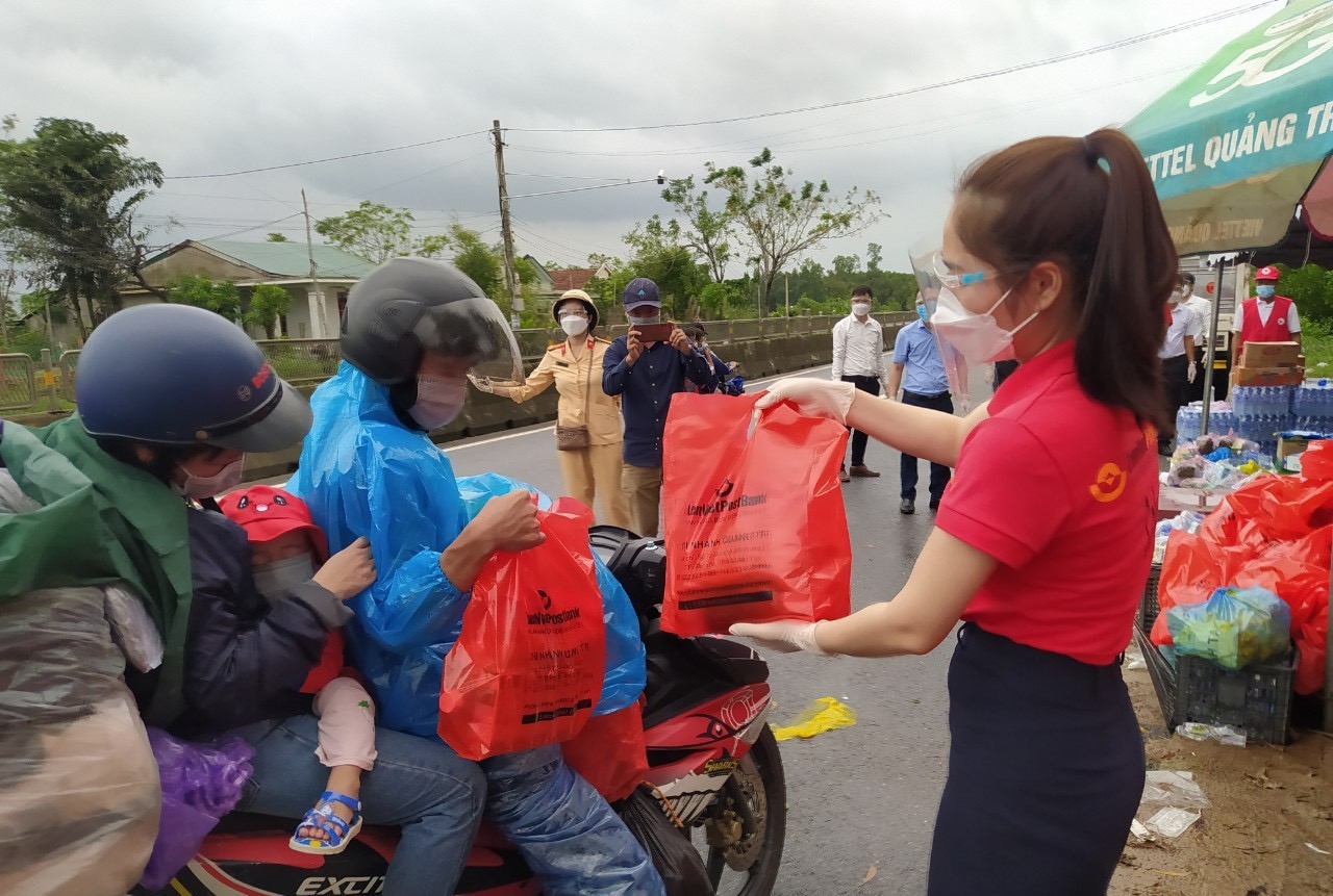 Trao tặng thức ăn và đồ dùng cho những người trở về bằng xe máy từ các tỉnh, thành phía Nam trên Quốc lộ 1A đoạn qua xã Hải Chánh, huyện Hải Lăng, tỉnh Quảng Trị. Ảnh: Thanh Thủy/TTXVN