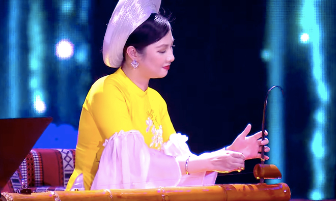 NSƯT đàn bầu Việt Nam Lệ Giang nổi bật với tà áo dài màu vàng.