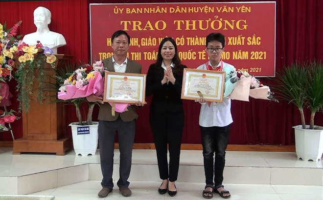 Đồng chí Lã Thị Liền -Phó Chủ tịch UBND huyện Văn Yên tặng hoa và trao thưởng cho thầy giáo Trần Phi Hùng và em Trần Quốc Thái.