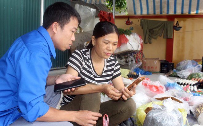 Đoàn viên thanh niên xã Đại Phác, huyện Văn Yên hướng dẫn các tiểu thương cài đặt, sử dụng ứng dụng thanh toán không dùng tiền mặt.