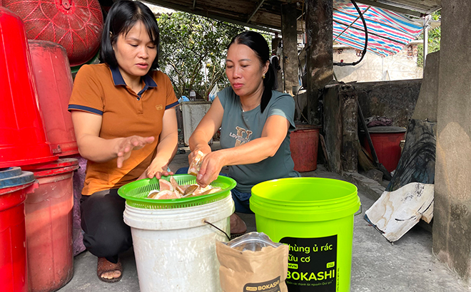 Cán bộ Hội Phụ nữ xã Cát Thịnh hướng dẫn người dân ủ rác hữu cơ bằng thùng ủ và men vi sinh.