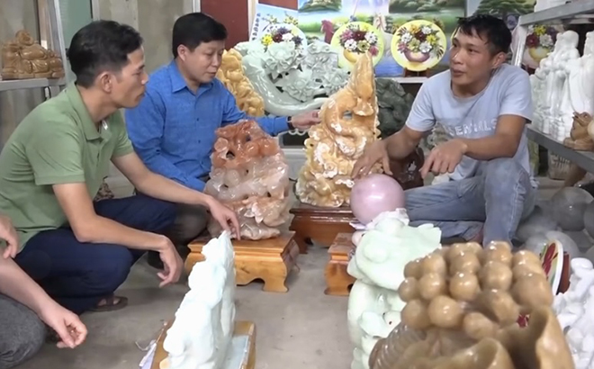 Anh Hoàng Văn Khương ở thôn Bến Muỗm, xã Vĩnh Lạc, huyện Lục Yên (bên phải) giới thiệu các tác phẩm điêu khắc đá mỹ nghệ.