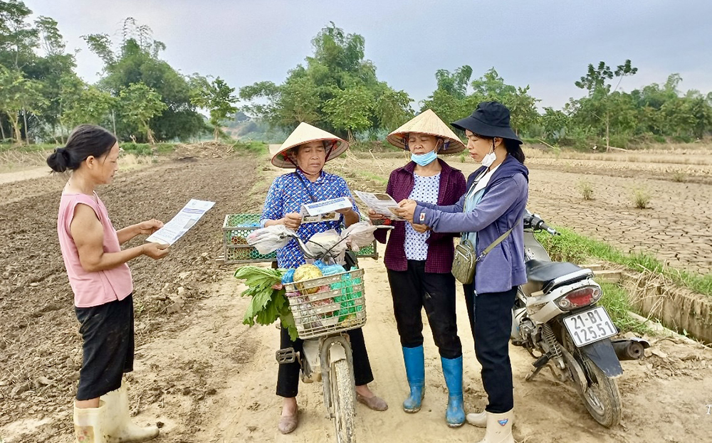 Viên chức Trung tâm Dịch vụ, Hỗ trợ phát triển nông nghiệp thành phố Yên Bái (ngoài cùng, bên phải) phát tờ rơi hướng dẫn nông dân xã Tuy Lộc phục hồi sản xuất nông nghiệp sau bão lũ.