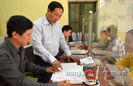 Ông Ngô Kim Ngọc (đứng) - Chủ tịch phường Hồng Hà trao đổi công việc với cán bộ chuyên môn tại bộ phận “một cửa”.
