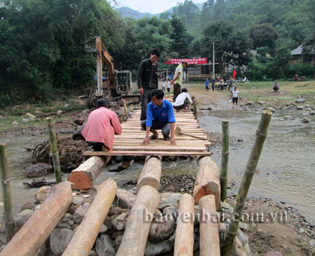 Anh Hà Văn Hưng (người ngồi giữa) cùng đoàn viên thanh niên xã Sơn Lương tham gia làm cầu qua suối.
