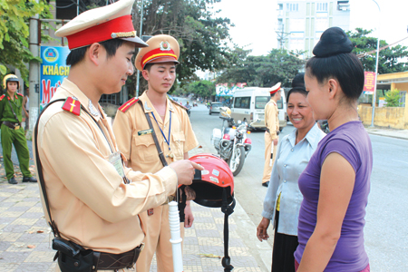Cảnh sát giao thông thị xã Nghĩa Lộ hướng dẫn nhân dân về chất lượng mũ bảo hiểm.