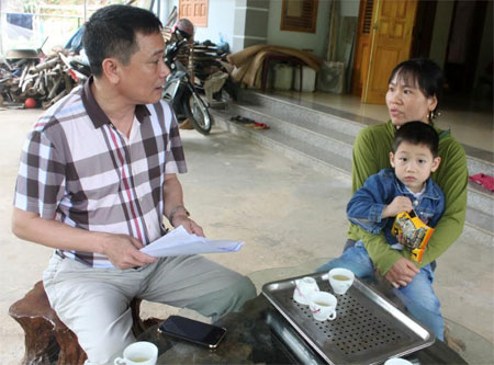 Cán bộ Bảo hiểm xã hội huyện Yên Bình tuyên truyền chính sách bảo hiểm y tế hộ gia đình cho người dân.