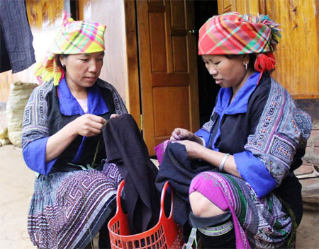 Tranh thủ những lúc rảnh rỗi, phụ nữ Mông thường may váy áo. 
(Ảnh: Hoài Anh)