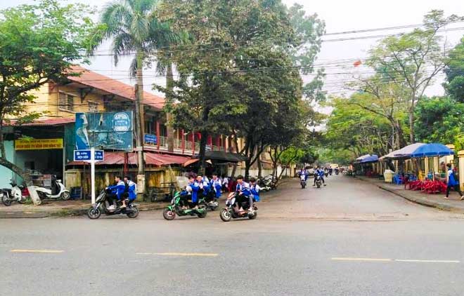 Tình trạng học sinh đi xe máy điện, xe đạp điện không đội mũ bảo hiểm diễn ra khá phổ biến trên địa bàn thị xã Nghĩa Lộ.