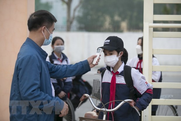 Đo thân nhiệt cho học sinh trước khi vào lớp học ở trường THCS Quán Bàu, thành phố Vinh.