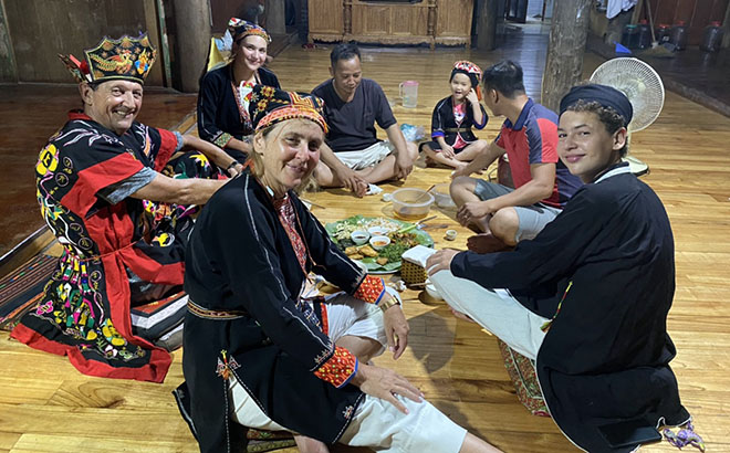 Du khách nước ngoài thích thú với trang phục và ẩm thực của người dân tộc Dao, xã Vũ Linh, huyện Yên Bình.