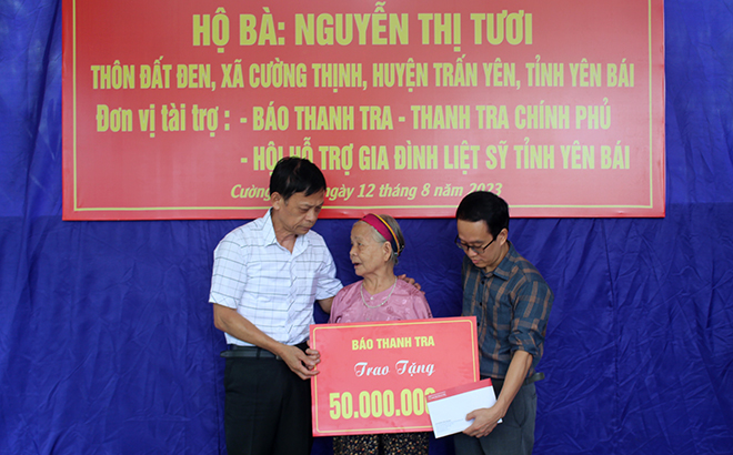 Dong Quang Hung, Chairman of the Association for Martyr Family Support, and donors hand over financial assistance to Nguyen Thi Tuoi who is a martyr's relative in Cuong Thinh commune, Tran Yen district.