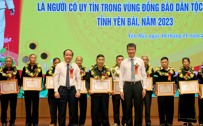 Standing Vice Secretary of the provincial Party Committee and Chairman of the provincial People’s Council Ta Van Long, and Vice Secretary of the provincial Party Committee and Chairman of the provincial People’s Committee Tran Huy Tuan present certificates of merit to exemplary prestigious persons of ethnic minorities in Yen Bai during the 2018 - 2022 period.