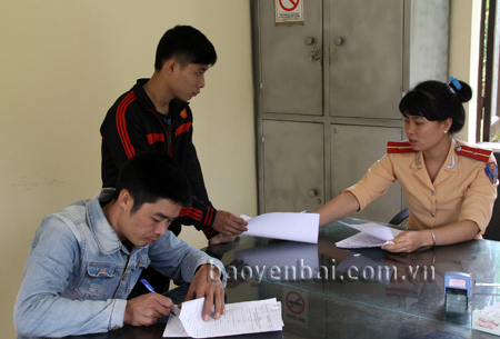 Cán bộ Đội Cảnh sát giao thông - Trật tự - Cơ động, Công an huyện Yên Bình hướng dẫn thủ tục cho người dân.