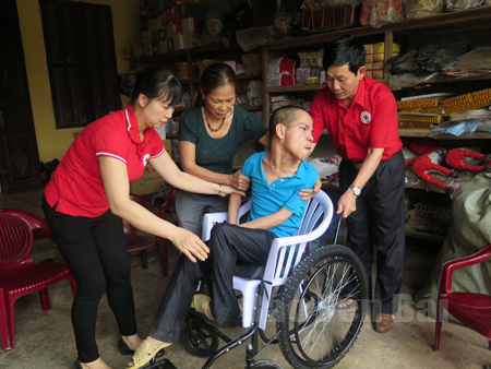 Đồng chí Nguyễn Bình Minh - Chủ tịch Hội Chữ thập đỏ tỉnh trao xe lăn hỗ trợ cho người khuyết tật tại huyện Trấn Yên.