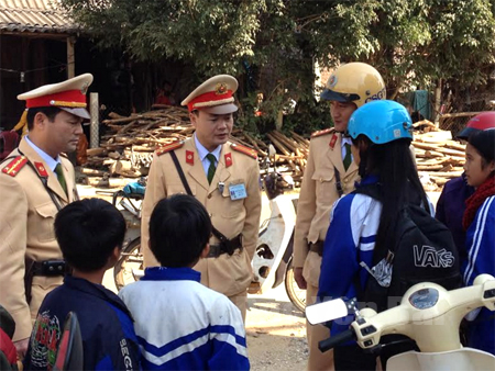 Lực lượng CSGT Công an tỉnh tuyên truyền, nhắc nhở học sinh đội mũ bảo hiểm khi tham gia giao thông. (Ảnh: Mạnh Cường)
