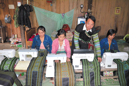 Anh Giàng A Măng hướng dẫn phụ nữ trong thôn sử dụng máy dệt thổ cẩm.