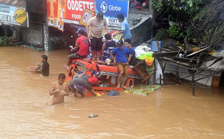 Người dân ngồi trên một chiếc xe đã ngập gần hết ở thành phố Cagayan de Oro của Philippines.