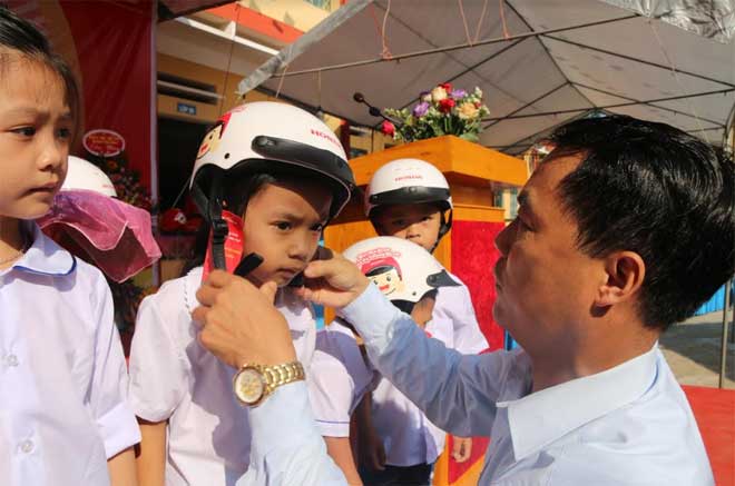Lãnh đạo xã Mông Sơn, huyện Yên Bình trao mũ bảo hiểm cho học sinh lớp 1 trong ngày khai giảng năm học 2019 - 2020.