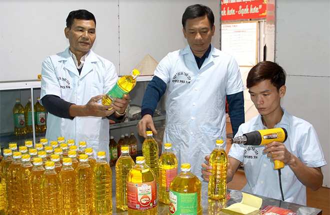 Ông Đàm Văn Việt - Chủ tịch Hội đồng Quản trị HTX Thái Sơn (đứng giữa) kiểm tra công đoạn đóng gói, dán tem sản phẩm dầu lạc đỏ.
