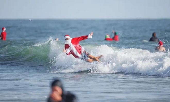 Một người lướt sóng trong trang phục Ông già Noel tham dự sự kiện từ thiện ở Florida hôm 24/12.