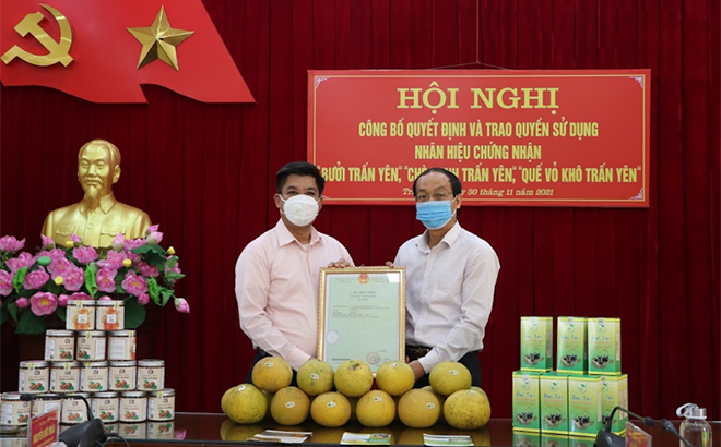 An official from the Yen Bai Department of Science and Technology handed over the trademark registration certificates to a representative from the Tran Yen People’s Committee.