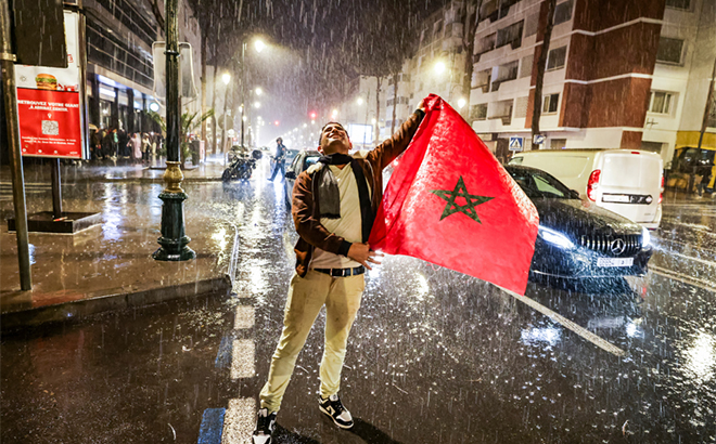 CĐV Morocco căng lá quốc kỳ dưới mưa trong lúc trận bán kết gặp Pháp diễn ra, tại thủ đô Rabat, ngày 14/12.