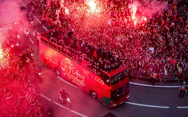 Người hâm mộ tập trung hai bên đường và đốt pháo sáng chào đón xe buýt chở đội tuyển bóng đá Morocco ở thủ đô Rabad hôm 20/12.
