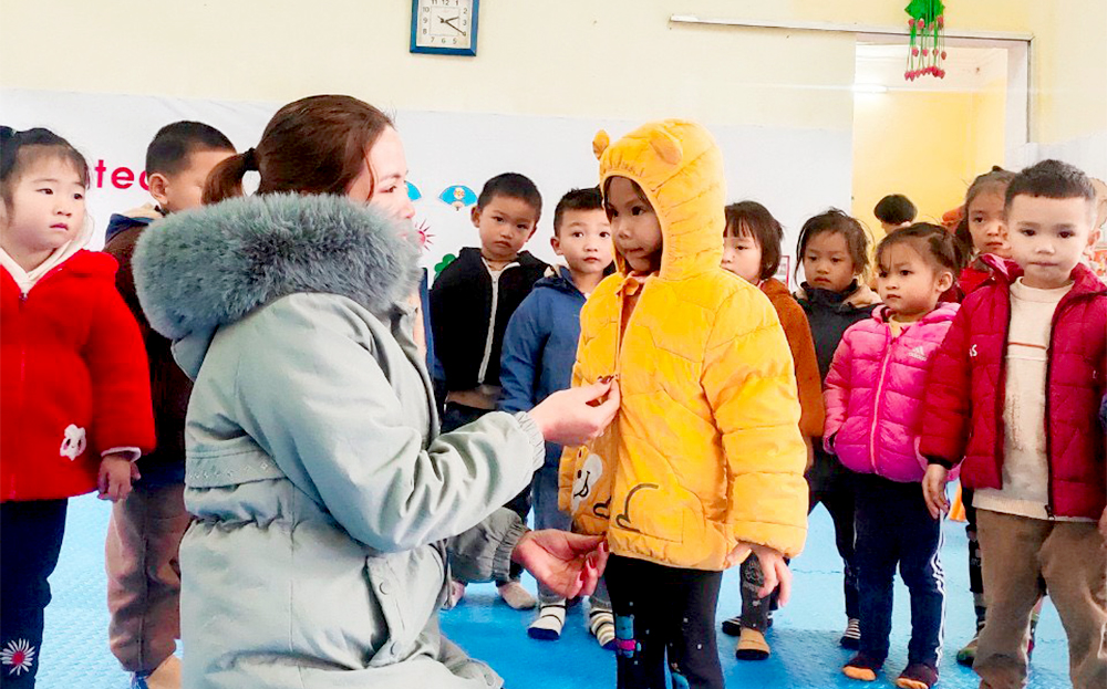 Cô giáo Trường mầm non Hoa Lan, xã Hát Lừu, huyện Trạm Tấu mặc áo ấm cho trẻ sau giấc ngủ trưa.