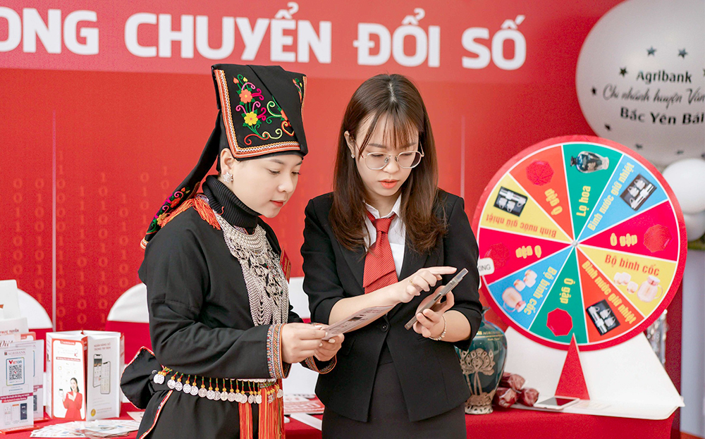 Cán bộ Agribank Chi nhánh huyện Văn Yên hướng dẫn người dân sử dụng các hình thức thanh toán không dùng tiền mặt.