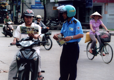 Cán bộ thanh tra giao thông Sở GTVT phát tờ rơi tuyên truyền Luật Giao thông đường bộ cho người dân.
