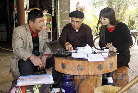 Ông Lạc Văn Sinh (giữa) trao đổi với cán bộ văn hóa huyện Yên Bình về các tài liệu đã sưu tầm Sình ca Cao Lan.