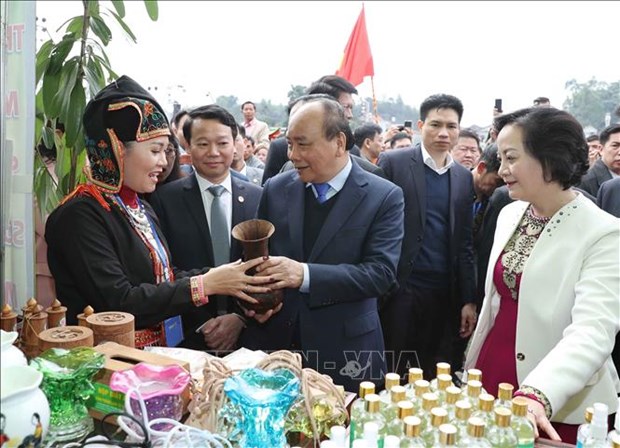 Prime Minister Nguyen Xuan Phuc takes a look at traditional products made by people in Tran Yen district, Yen Bai province on his visit here.