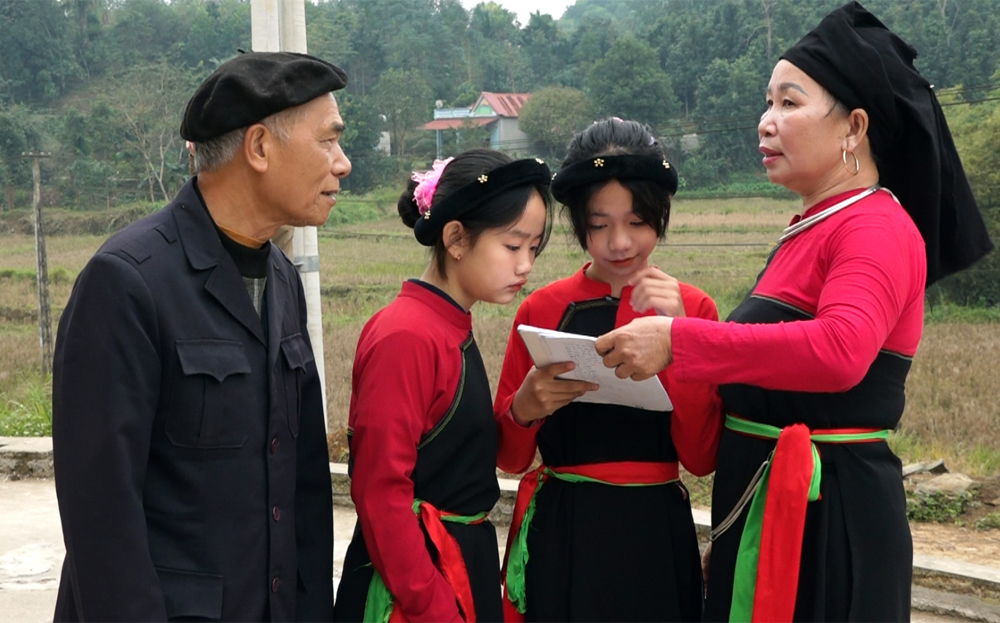 Nghệ nhân ưu tú Lạc Tiên Sinh (bên trái) trực tiếp truyền dạy chữ viết cho các học viên ở thôn Khuôn La.