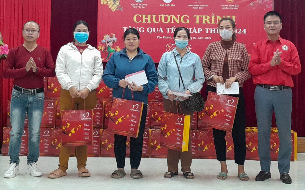 Đại diện Quỹ Thiện tâm - Tập đoàn Vingroup và Hội Chữ thập đỏ huyện Yên Bình trao quà cho các hộ nghèo.