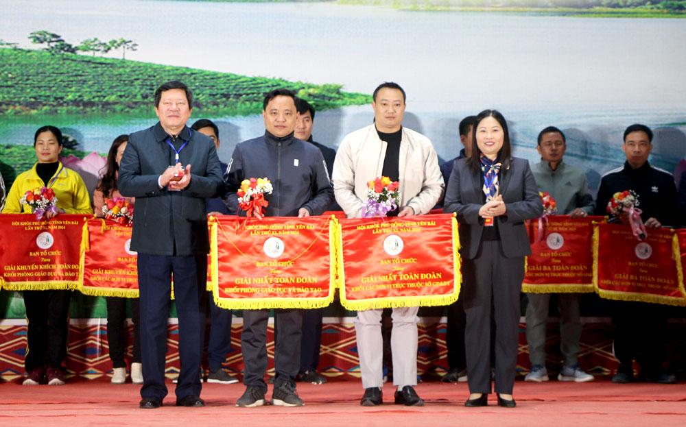 Vice Chairman of the provincial People's Committee Vu Thi Hien Hanh and Director of the provincial Department of Education and Training Vuong Van Bang present the flags honouring teams with the best performance to the Yen Bai city’s Department of Education and Training, and the provincial Ethnic Boarding High School.