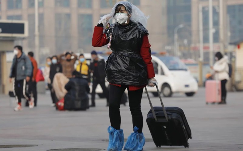 Một nữ hành khách ở ga tàu hỏa Bắc Kinh dùng túi nylon che đầu, chân và thân để phòng virus corona chủng mới Covid-19.