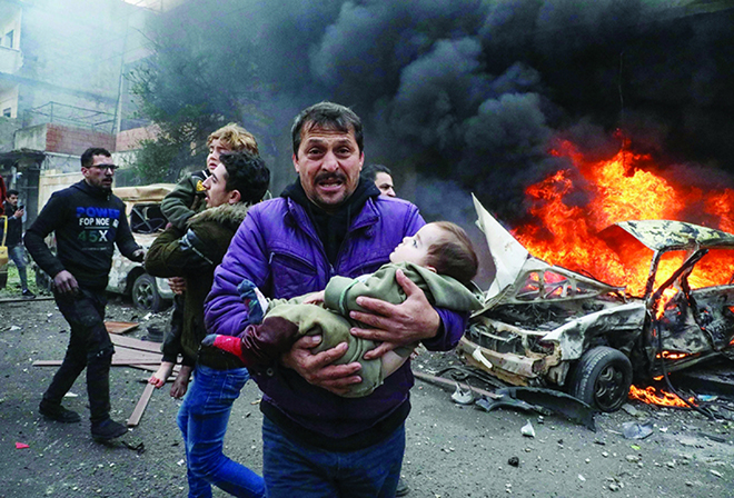 Một người cha ôm đưa con nhỏ chạy khỏi hiện trường vụ đánh bom ở Aleppo.