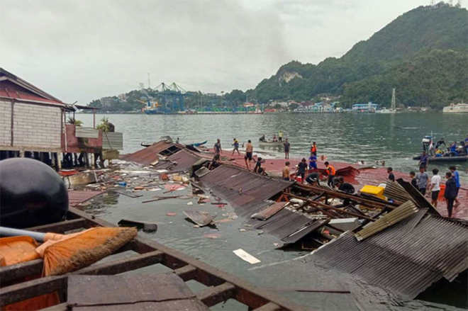 Mọi người đứng trên mái nhà bị sập xuống sông ở Jayapura, tỉnh Papua phía Đông Indonesia.