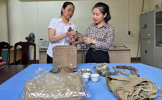 Phóng viên Thu Trang Báo Yên Bái (bên phải) cùng cán bộ Bảo tàng tỉnh tìm hiểu những hiện vật lịch sử của cuộc chiến đấu bảo vệ biên giới phía Bắc.