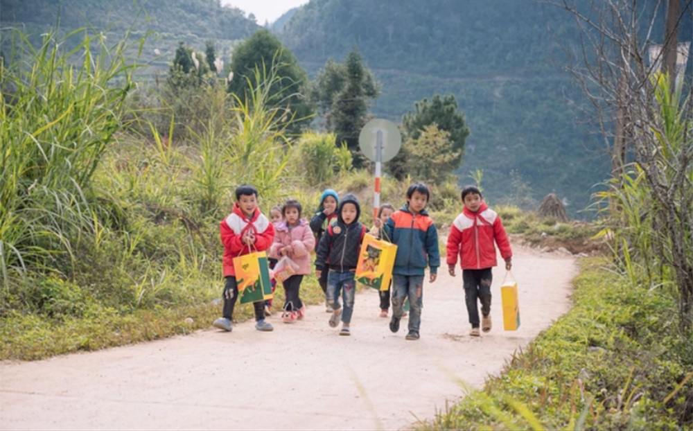 Các em học sinh Trường phổ thông dân tộc bán trú Tà Lủng (Mèo Vạc, Hà Giang) tung tăng về nhà với phần quà Tết. Ảnh minh hoạ.