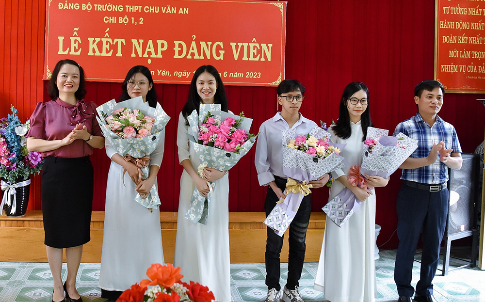 Đồng chí Vũ Minh Huê - Phó Bí thư Thường trực Huyện ủy Văn Yên tặng hoa chúc mừng các đảng viên mới là học sinh của Đảng bộ Trường THPT Chu Văn An. 
