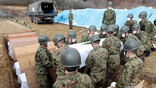 Những người lính tiến hành chôn cất thi thể nạn nhân trong lễ tang tập thể.